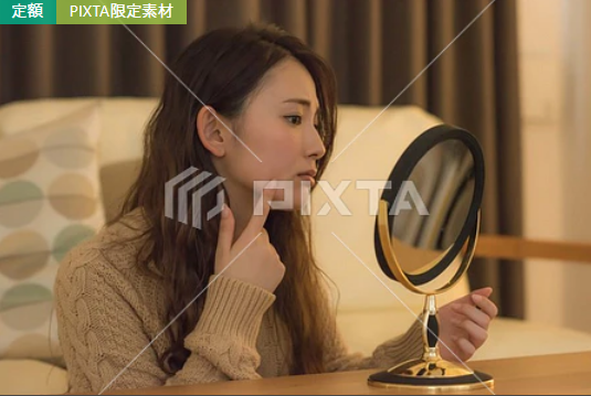 鏡を見ながら肌の変化を感じる女性